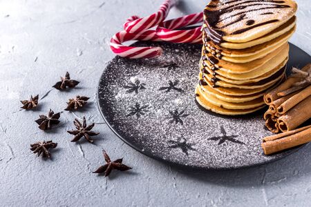 Fresh sweet pancakes with chocolate jam, cinnamon sticks and marshmallows on a gray background with place for your textの写真素材