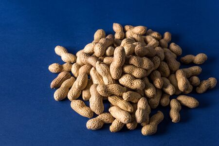 A pile of roasted peanuts on a trendy blue background with place for design and your text. concept. agricultureの写真素材