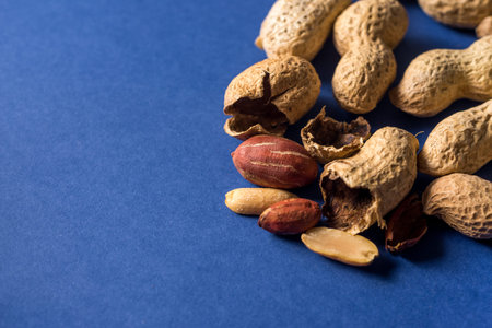 A pile of roasted peanuts on a trendy blue background with place for design and your text. concept....