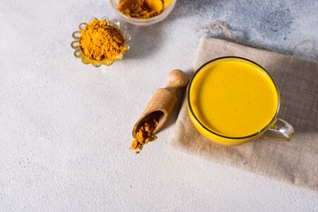 Golden turmeric milk on the white background with spices cinnamon and ingredientsの写真素材