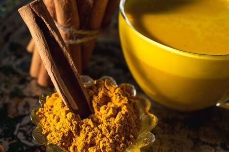 Golden turmeric milk on the dark background with spices cinnamon and ingredientsの写真素材