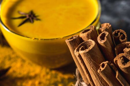 Golden turmeric milk on the dark background with spices cinnamon and ingredientsの写真素材