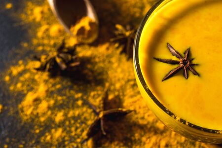 Golden turmeric milk on the dark background with spices cinnamon and ingredientsの写真素材