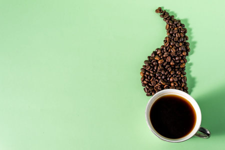 Coffee cup and coffee beans on a light mint background