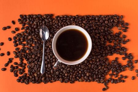 cup of aromatic coffee and coffee beans on an orange trendy background with space for textの写真素材
