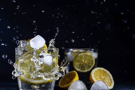 splash Gin and tonic cocktail with lemon slices Ice cube falls into water with lemon Copy space, lemonadeの写真素材