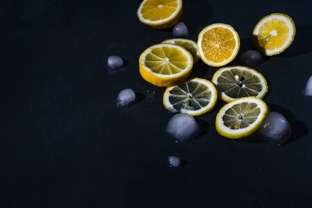 cut lemons with lemon slices and ice cubes against dark background. Top view. Close-upの写真素材