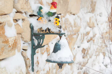 Cock bell on stone wall in winterの写真素材