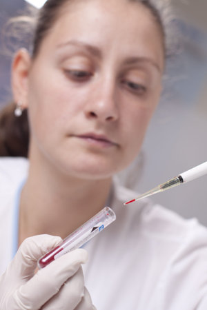 Woman taking sample from test tube with micro pipetteの写真素材