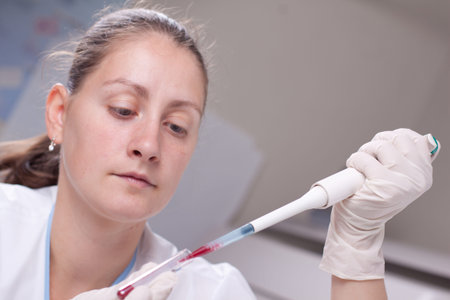 Woman taking sample from test tube with micro pipette