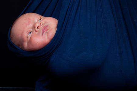 Newborn baby in blue slingの写真素材