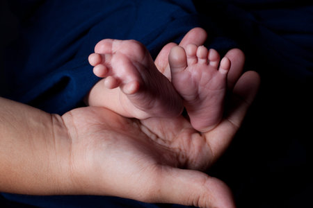 Mother holding baby feets on bark background
