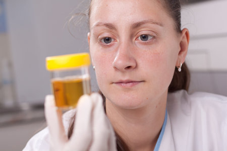 Woman examin urine container in laboratory environmentの写真素材