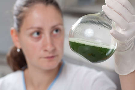 Woman examine bottle with chemical in laboratoryの写真素材