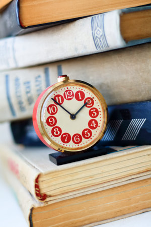 analog retro red alarm clock on a heap of old booksの写真素材