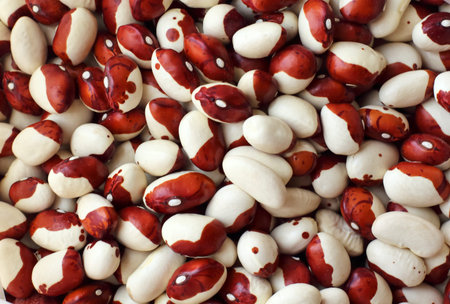 White kidney beans with red spots pours out on the marble sutface close-up. vertical