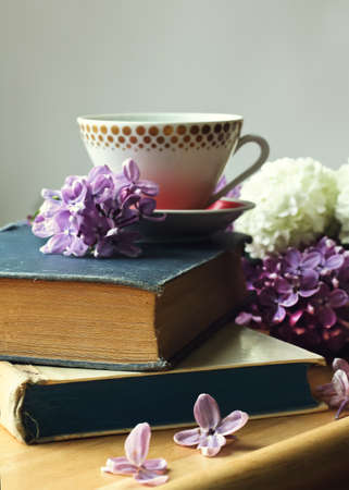 cup of tea on the stack of old books and spring lilac flowersの写真素材