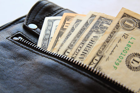dollar bills peeking out of the black leather bag, close-upの写真素材