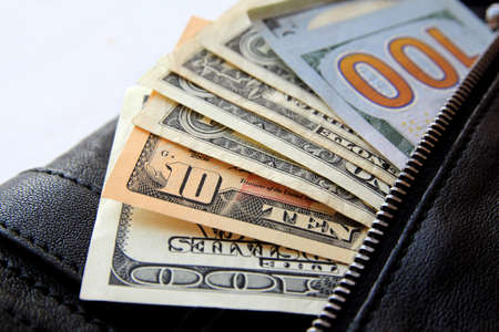 dollar bills peeking out of the black leather bag, close-upの写真素材