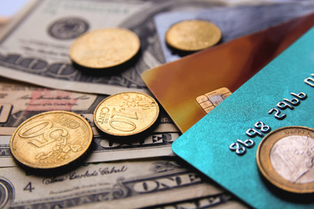 Stack of credit cards with american dollars and euro coins, close-up view.