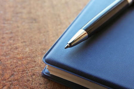 blue notebook and ball pen on an old  wooden background, close up view with copy space.の写真素材