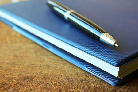 blue notebook and ball pen on an old  wooden background, close up view with copy space.の写真素材