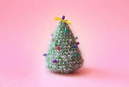 Knitted Christmas tree bound of green yarn with multicolored pins on it. Christmas holiday concept in minimalism style.の写真素材