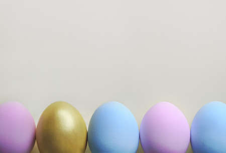 A row of pastel colored Easter eggs on white background. Festive easter background in minimalism style.の写真素材