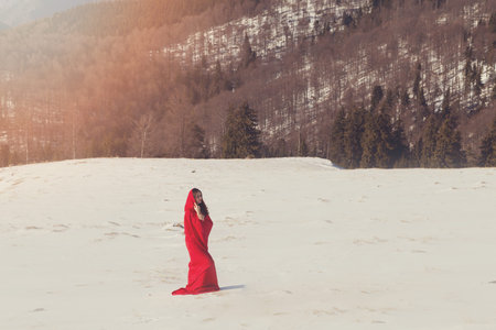 Young woman in red riding hood costume, on a snowy mountain backgroundの写真素材