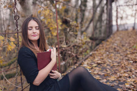 Autumn portrait of a young woman reading a book in the natureの写真素材