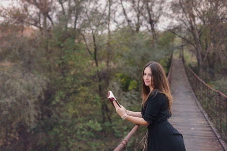 Autumn portrait of a young woman reading a book in the natureの写真素材