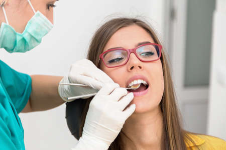 Young woman patient at the dentist, at the dental clinic. Young woman dentist treating her patientの写真素材