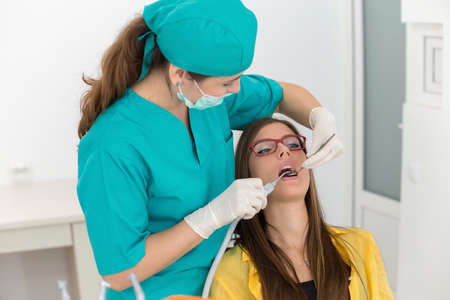 Young woman patient at the dentist, at the dental clinic. Young woman dentist treating her patientの写真素材