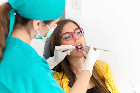 Young woman patient at the dentist, at the dental clinic. Young woman dentist treating her patientの写真素材