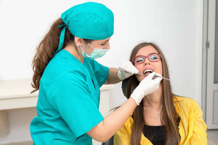 Young woman patient at the dentist, at the dental clinic. Young woman dentist treating her patientの写真素材