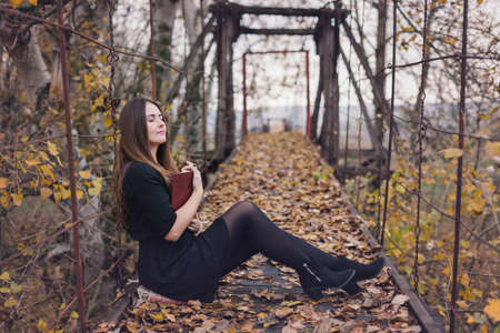 Autumn portrait of a young woman reading a book in the natureの写真素材