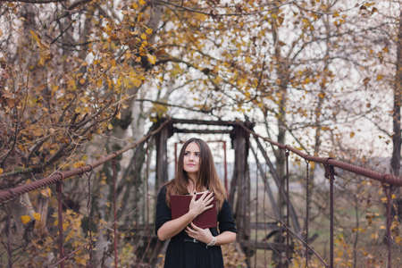 Autumn portrait of a young woman reading a book in the natureの写真素材