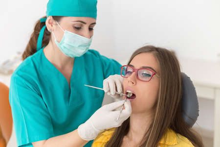 Young woman patient at the dentist, at the dental clinic. Young woman dentist treating her patientの写真素材