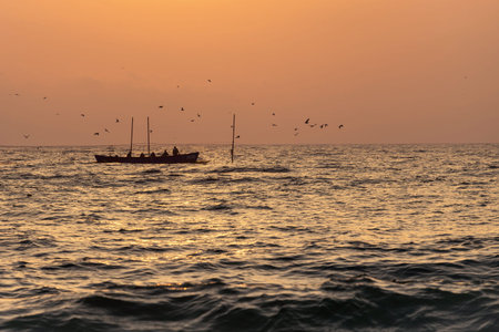 Fishermen silhouettes on boat, at sunrise