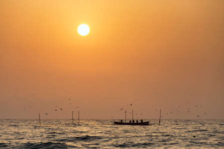 Fishermen silhouettes on boat, at sunriseの写真素材