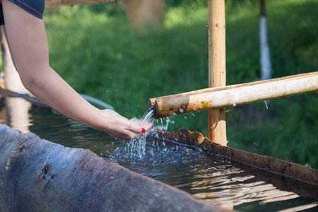 Young woman refreshing her hands in mountain springの写真素材