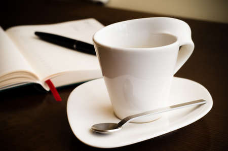 Coffe at the workplace with a blank journal on the backgroundの写真素材