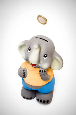 Smilling sweet elephant piggy bank with coin falling into itの写真素材
