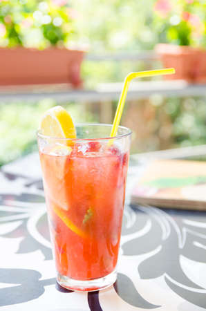 Strawberry and lemon cocktail with a yellow straw and a slice of lemon on a restaurant tableの写真素材