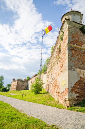 Medieval fortress of Brasov with the romanian flag and high brick wallsのeditorial素材