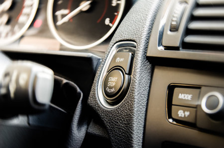 Auto start and stop button on a modern premium car interior suggesting fuel economy, modern...