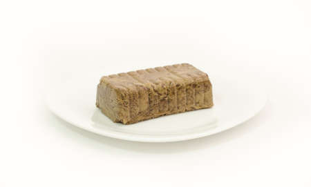 Traditional greek turkish romanian halvah dessert made from sunflower seeds and cocoa on a white plate on an isolated backgroundの写真素材