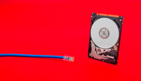 Cloud storage concept suggested by a internet network cable and a open hard disk on a red alerted...