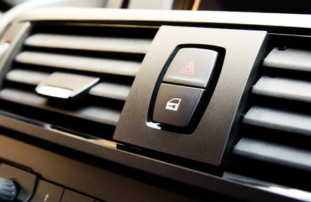 Detail of car interior with emergency button and door lock button next to the air conditioning vent...