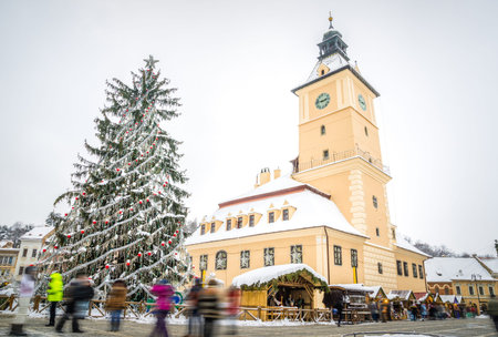 Brasov old medieval town hall in Sfatului Square on a cold winter day with a decorated Christmas Tree white snow and people in Transylvania region of Romaniaの写真素材